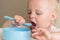 Boy learning to eat. cute messy baby eating vegetables with spoon by yourself in highchair