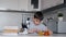 A boy learns biology using a microscope and makes notes in a notebook. Homework. Left camera movement