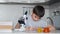 A boy learns chemistry using a microscope and makes notes in a notebook. Homework. Left camera movement