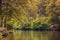 Boy in life jacket doing nature sports canoeing, with a orange canoe on wild river in a autumn color theme. forest scene with