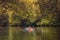 Boy in life jacket doing nature sports canoeing, with a orange canoe on wild river in a autumn color theme.  forest scene use as