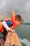 Boy in life vest leaning over boat railing