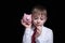 Boy listens attentively to the pink piggy bank. Business concept. Black background