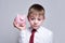 Boy listens attentively to the pink piggy bank. Business concept. Light background