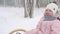 Boy and little girl in pink jumpsuit sledding on snowy winter day. Parents pull sled with son and daughter on snowfall