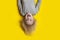 Boy with long blond hair on bright yellow background. Portrait of cheerful boy, upside down