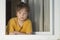 Boy look in window in Pandemic isolation - Child in windowsill during coronovirus, covid-19