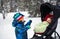 Boy Looking at Baby in a Stroller in a Snowy Forest