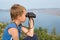 Boy looking through binoculars of the mountain.