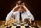Boy looking at Chess Board Checkmate holding Head in Hands. Stressed Teenager in Business Shirt thinking about Strategy