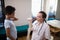 Boy looking at female therapist explaining with artificial spine