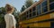 Boy looking out schoolbus window waving to mom. Mother sending air-kiss to son.