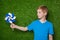 Boy looking at pinwheel over grass