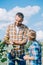 boy looking at smiling father touching sunflower