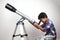 A boy looks through a telescope