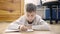 A Boy lying on the floor in her room doing homework. Horizontal shot.