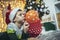 Boy lying on front on floor by christmas tree, blowing a balloon surrounded by gifts