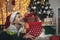 Boy lying on front on floor by christmas tree surrounded by gifts