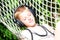 Boy lying in a hammock and listen to music on headphones. Summer