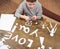 Boy makes origami - car and family, children, parent, I love you text, top view on wood background