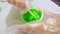 A boy making green slime at home, DIY project, chemistry experiment, he pours the ingredients into a container and mixes