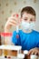 Boy in mask-respirator sits at table with chemical reagents