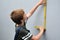 Boy measures the wall with the help of a folding rule