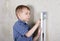 Boy measuring vertical of wall by level