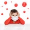 A boy in a medical mask holds on to his head. Around the viruses.