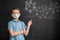a boy in a medical mask points to a chalk drawing of the coronavirus on a black blackboard.
