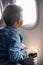 A boy in a medical mask sits in an airplane seat.