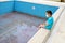 A boy with medical mask sits by an empty pool. Concept summer 2020. No tourism