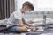 A boy in a medical mask sits in front of a laptop at home in bed. Distance learning