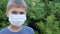 Boy with medical protective mask looking at camera. Kid standing outddors