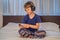 Boy meditates on bed using meditation app. sport, technology and healthy lifestyle concept
