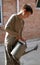 Boy with metal watering-pot against brickwall