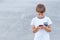 Boy with mobile phone playing game, using apps. Gray urban background. Childhood, technology, leisure concept