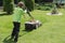 Boy mows grass in the yard with a lawn mower. the child helps adults in everyday activities.