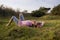 Boy in nature, lying on grass and looking at the camera.