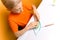 Boy in an orange T-shirt is sitting at a white table and pinching the twisted paper thin strips to give them an interesting