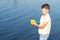 Boy outdoors by the lake playing with a water gun, water spray, summer games