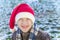 Boy outside wearing a knitted santa cap, laughing and scrunching