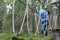 Boy overcoming hanging ropes obstacle in forest