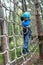 Boy overcoming mesh obstacle in forest adventure park
