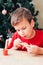Boy paints wooden dinosaur toy for Christmas tree