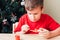 Boy paints wooden dinosaur toy for Christmas tree