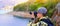 Boy photographer holding digital camera and shooting landscape of lake in the mountains