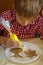 Boy in a plaid shirt is decorating the cookies in the shape of an angel with yellow cream