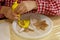 Boy in a plaid shirt is decorating with yellow cream the cookies in the shape of an angel and a star