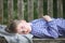 A boy in a plaid shirt lies in the garden